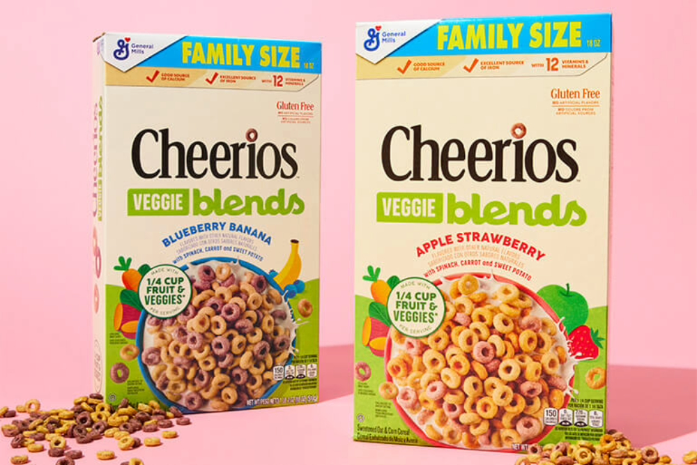 Two family sized Cheerios Veggie Blends boxes side by side in front of a pink background. Blueberry banana flavor on the left, and apple strawberry on the right